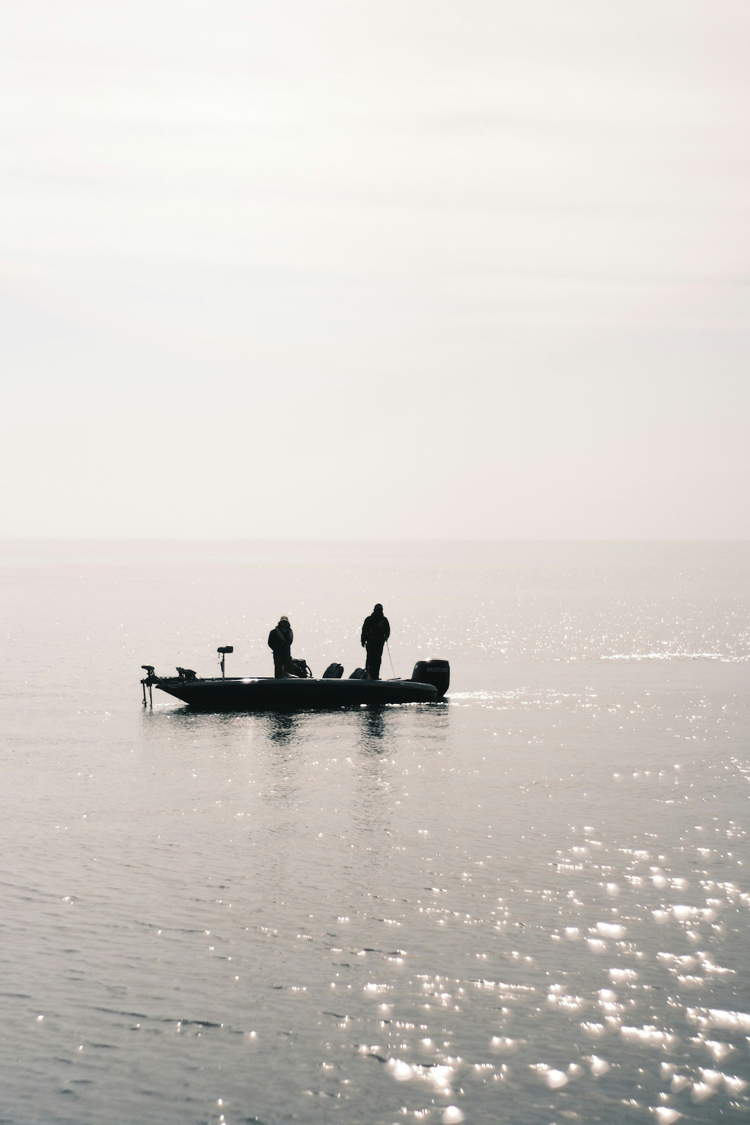 静かな海の上に浮かぶ小舟と二人の釣り人