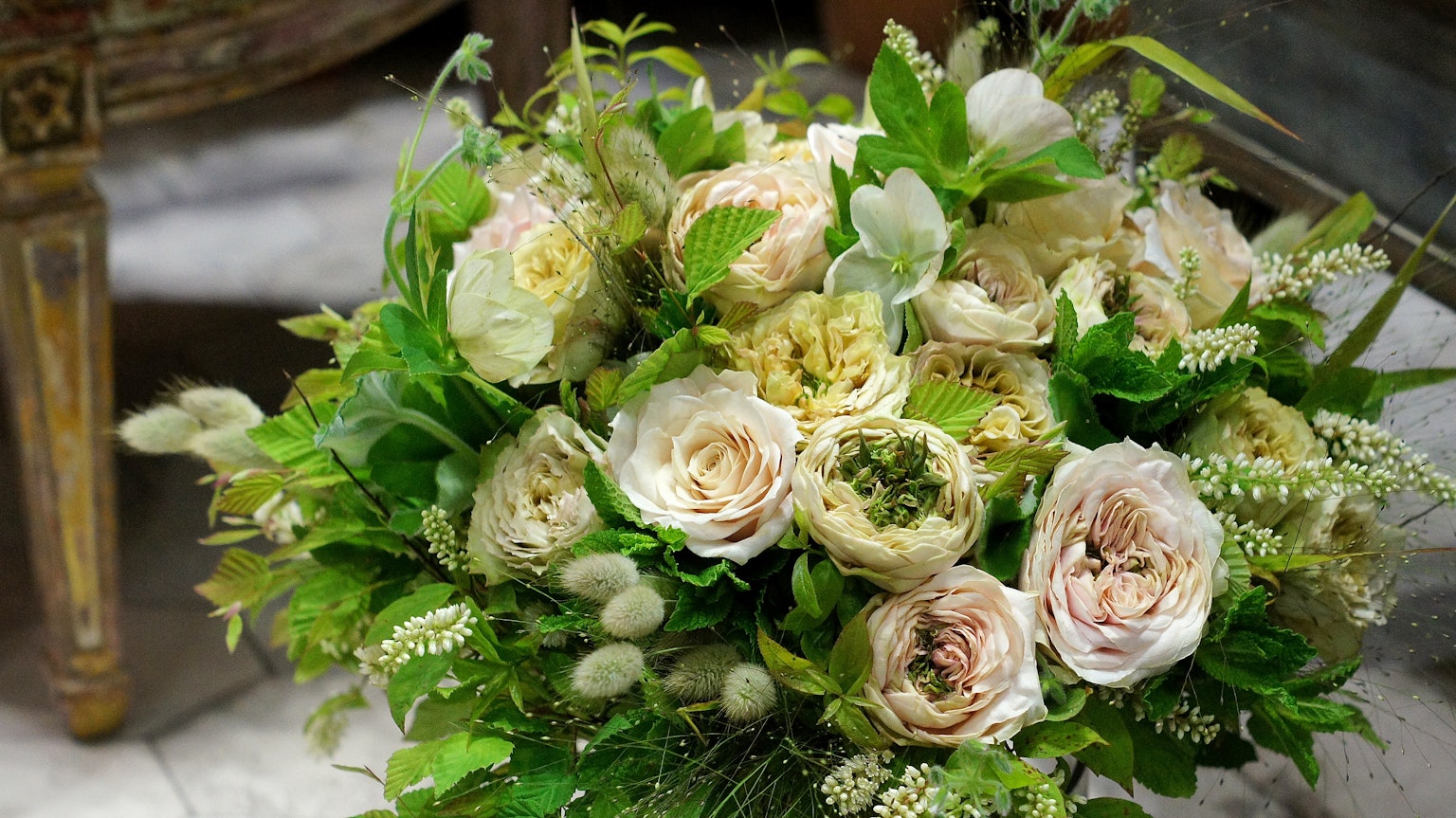 Un beau bouquet avec des roses couleur crème et de nombreuses feuilles vertes