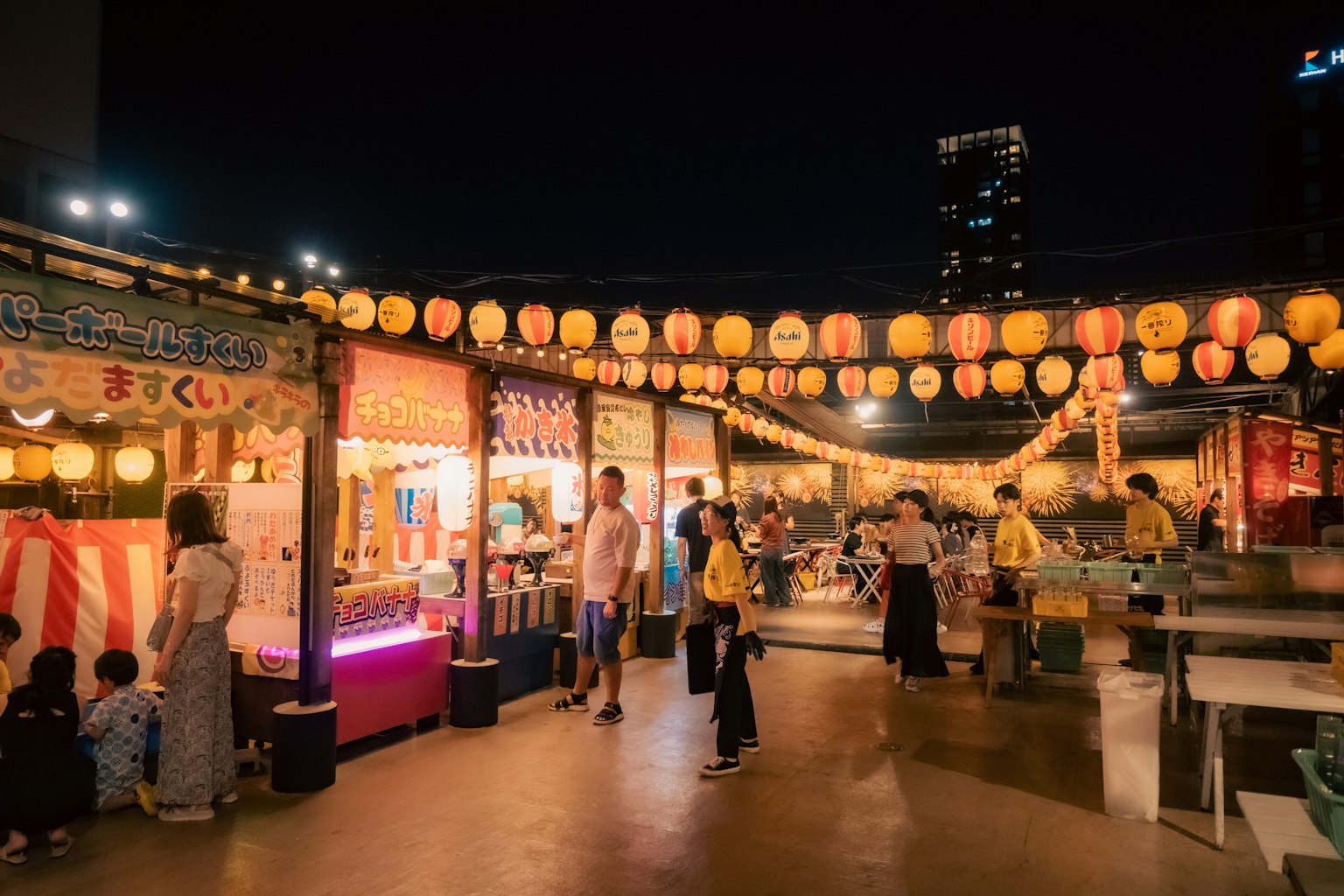 Escena vibrante de festival con puestos de comida y faroles iluminados por la noche
