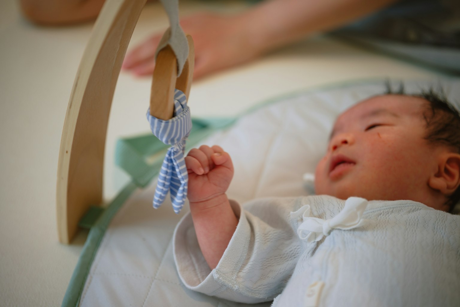 ทารกยื่นมือไปหาของเล่นที่แขวนอยู่ด้วยสีหน้าเต็มไปด้วยสมาธิ