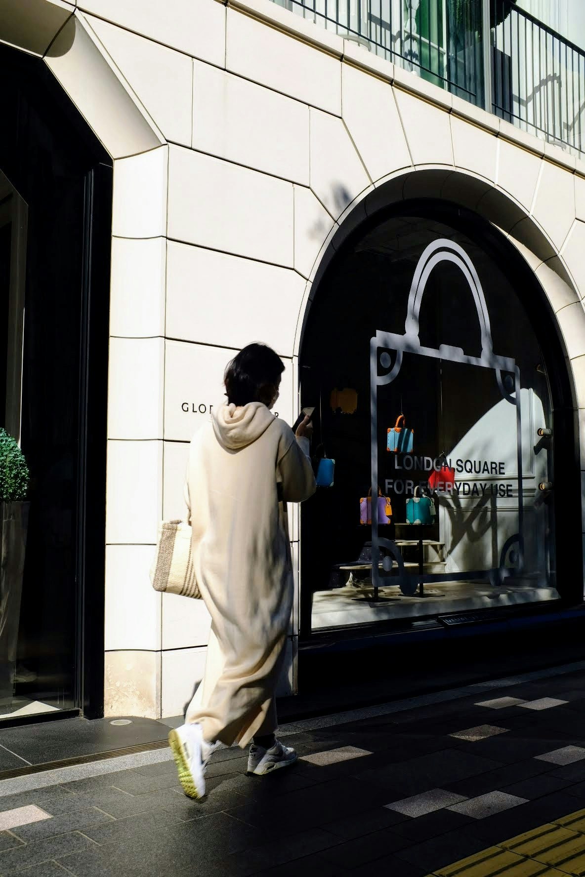 A person walking in front of an arched storefront entrance