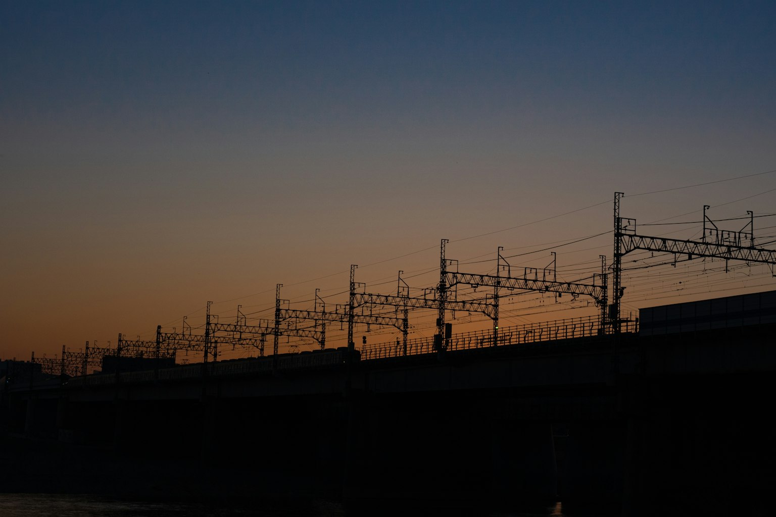 Silhouette of railway tracks and overhead wires at dusk