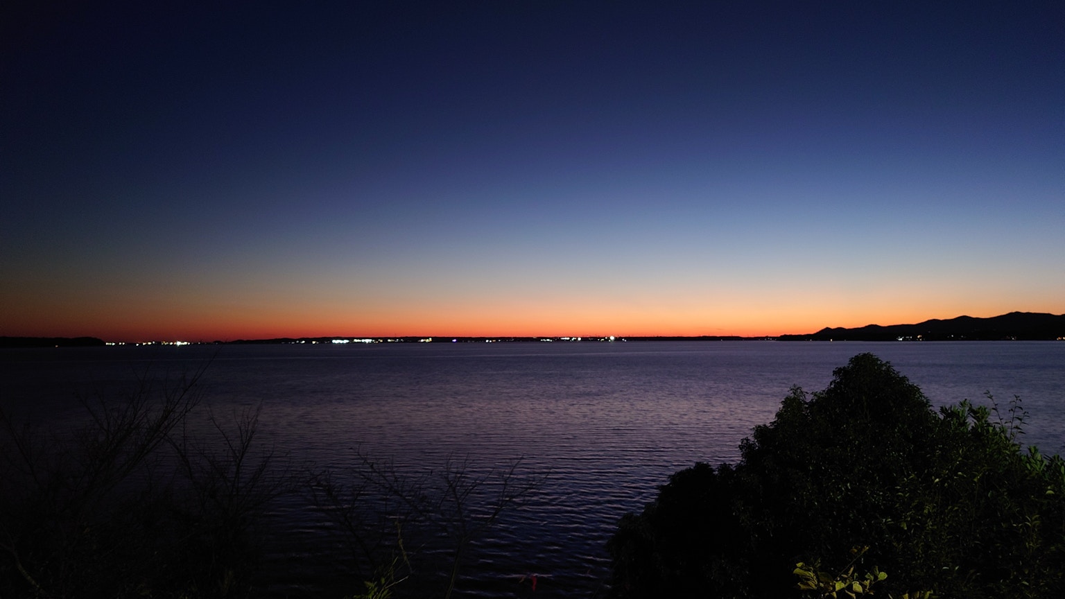 Serene lake surface reflecting the dusk sky and surrounding nature