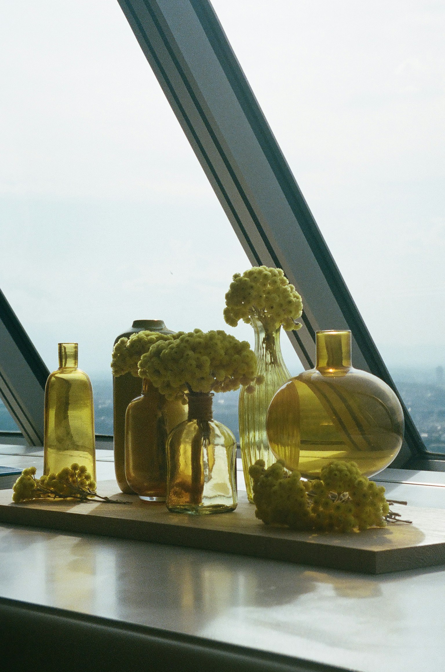 Gelbe Flaschen und Blumenarrangement auf einer Fensterbank