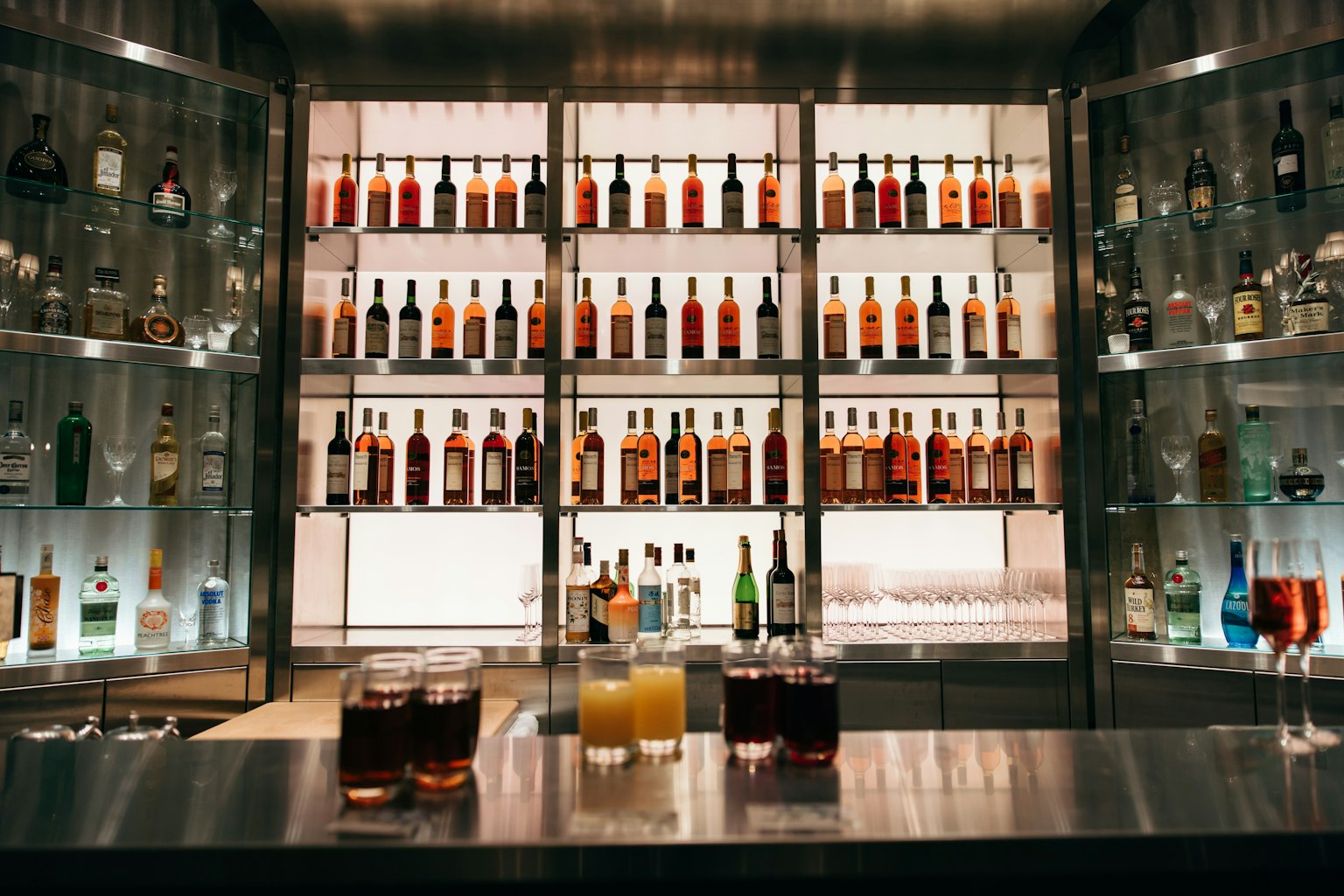 Cocktail su un bancone di bar con uno sfondo di bottiglie di liquore illuminate
