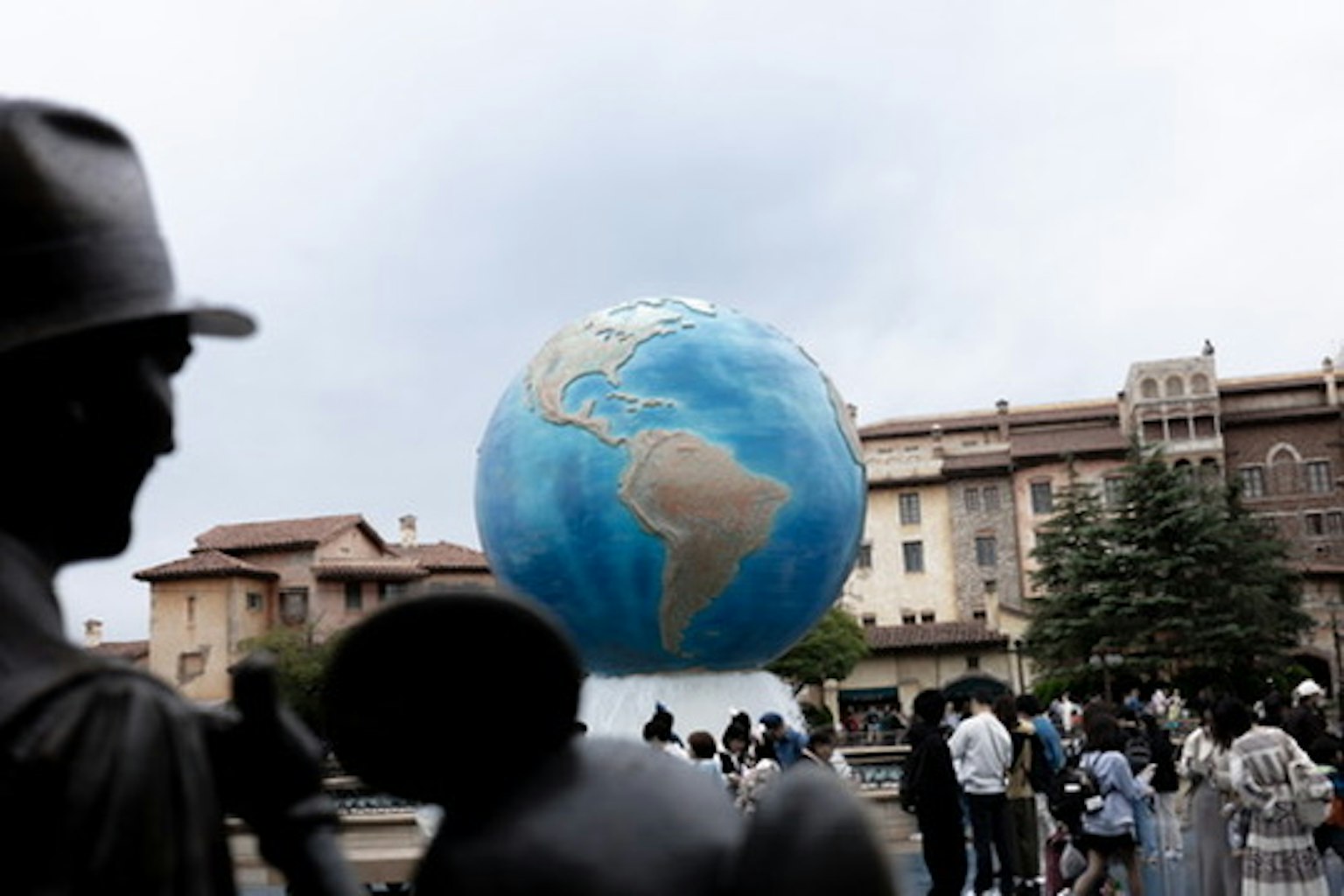 Sebuah patung globe biru dengan orang-orang berkumpul di plaza