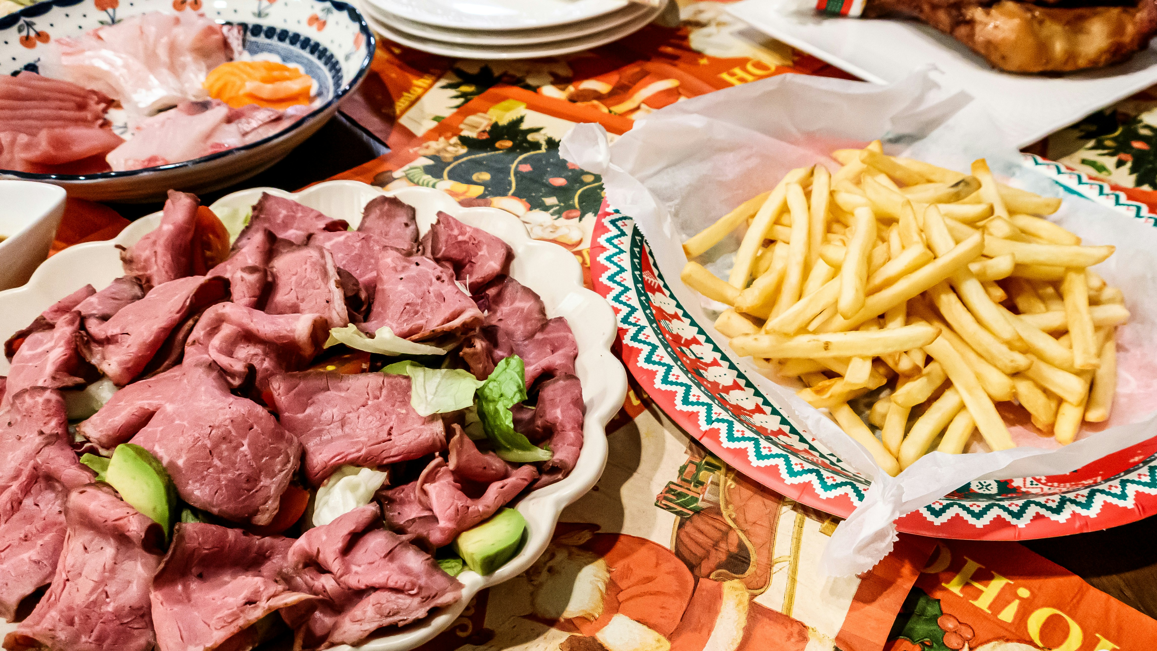 色鮮やかなテーブルクロスの上に並ぶ肉の盛り合わせとフライドポテト