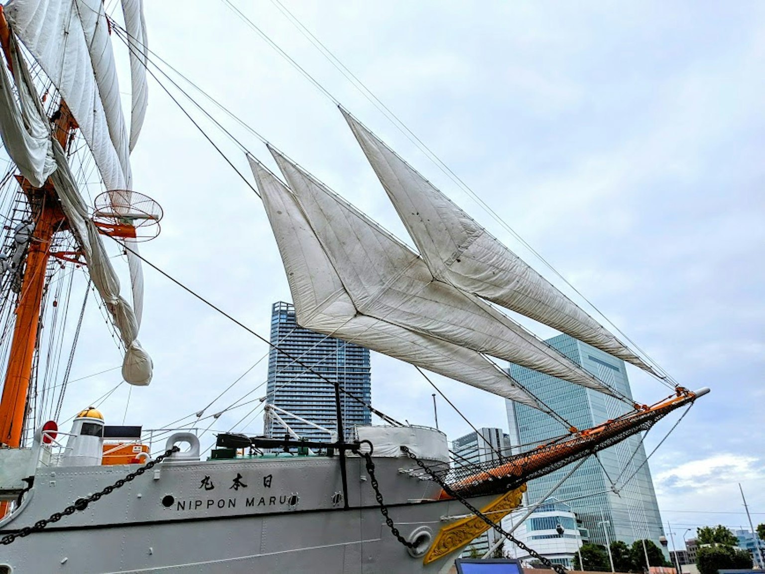 Kapal layar putih dengan gedung modern di latar belakang