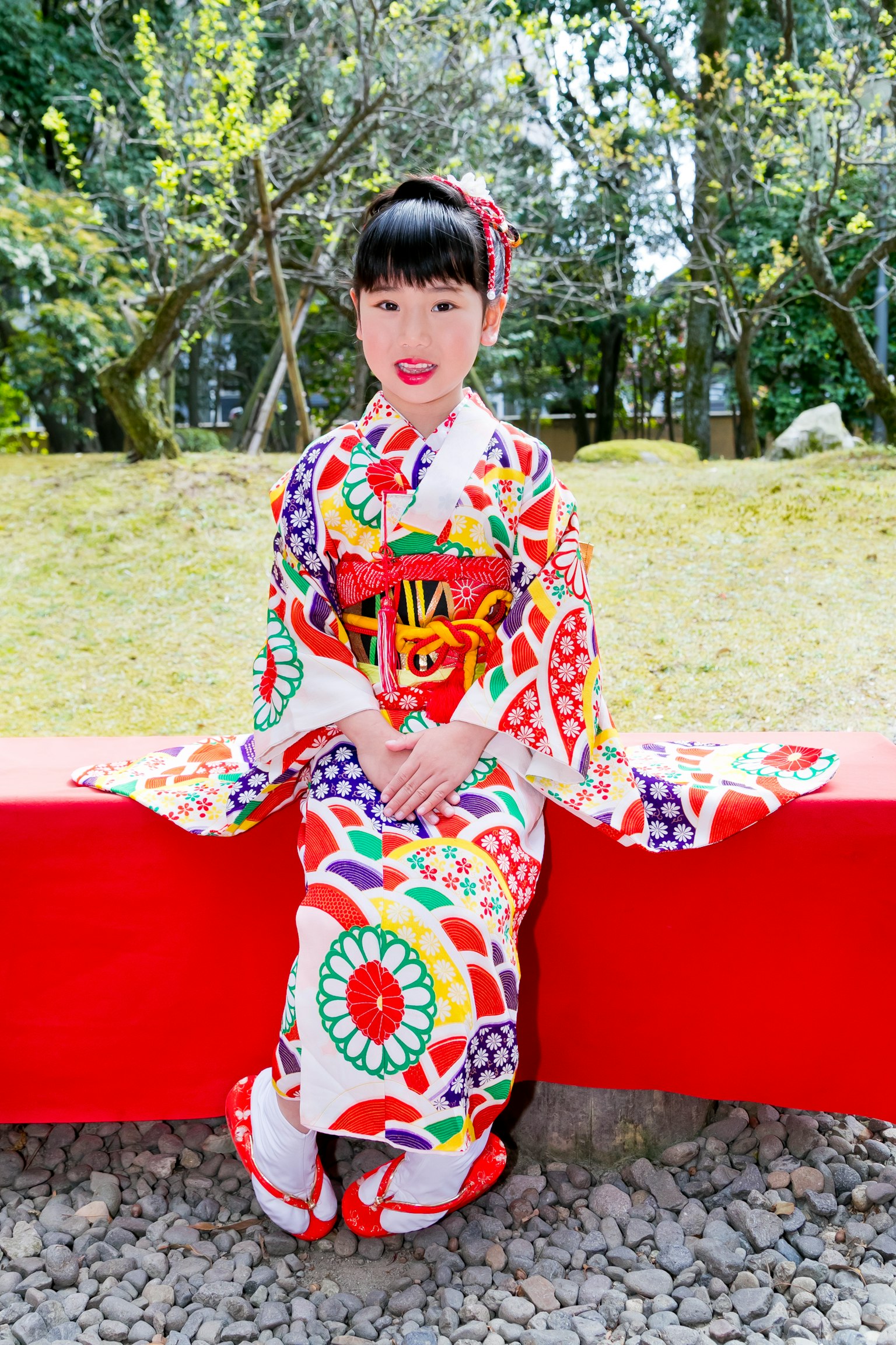 Fille en kimono coloré assise sur un banc rouge