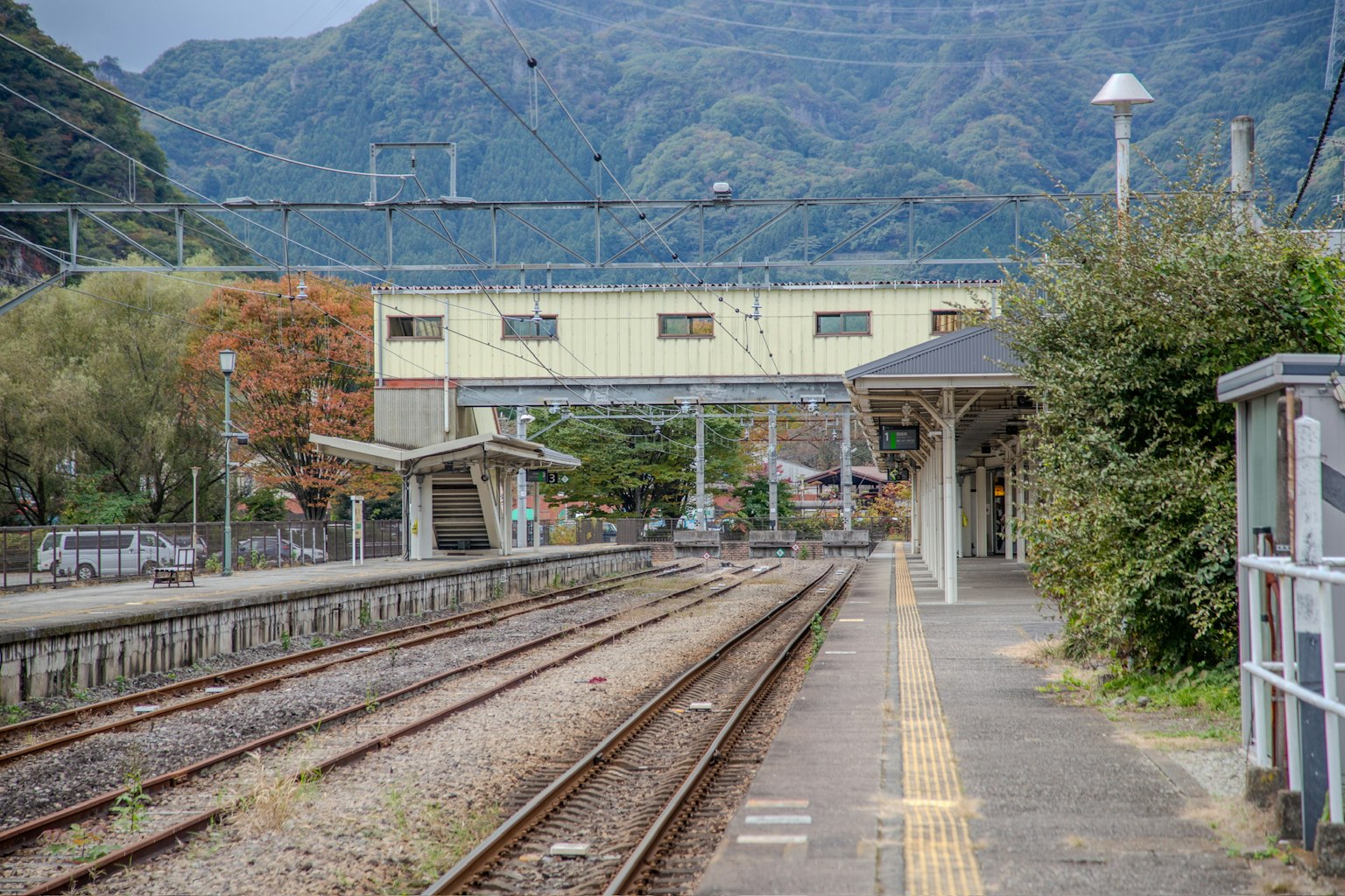 Quiet train station scene with mountain background featuring tracks and platform
