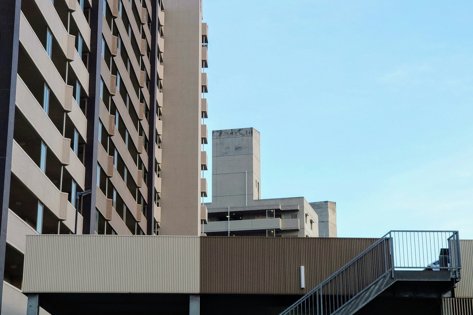 Vista de un edificio de gran altura con cielo azul y una escalera de metal