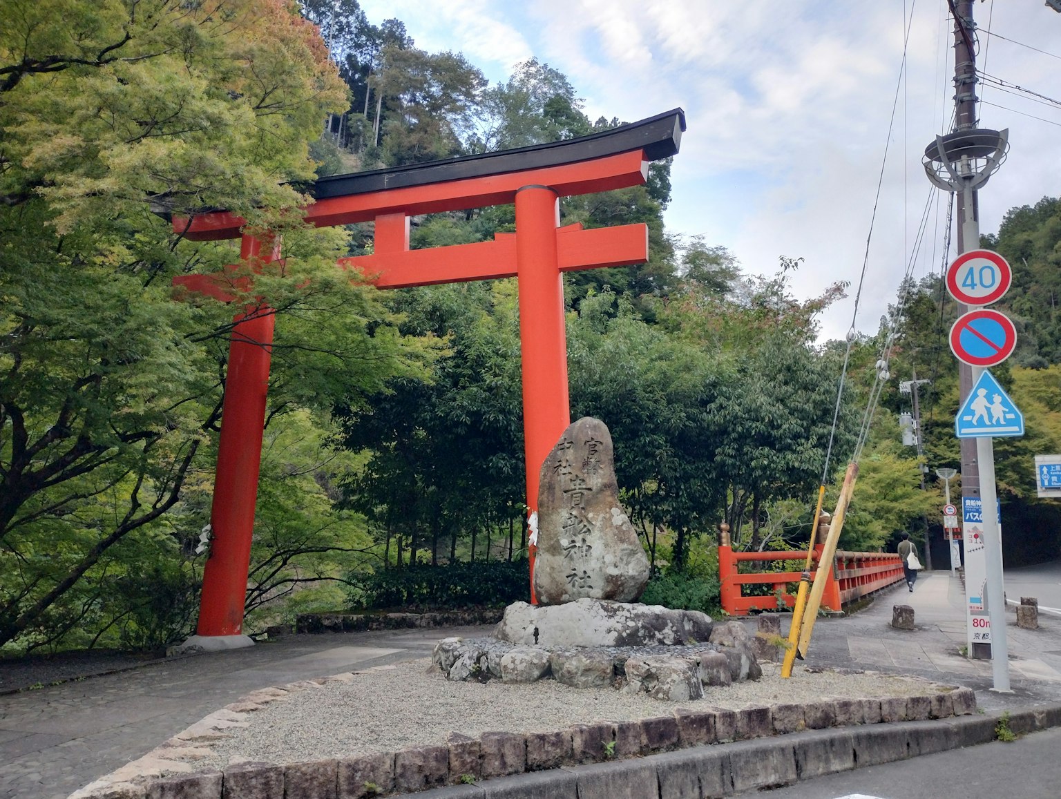 Portale torii rosso circondato da vegetazione e monumento in pietra