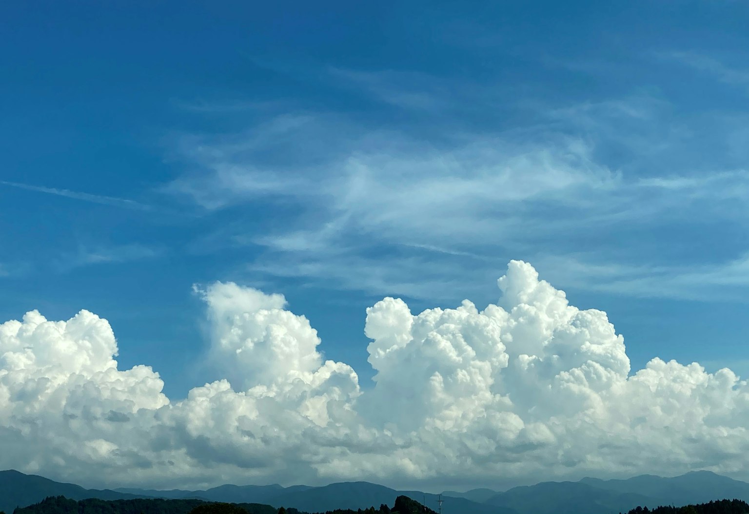 White clouds floating in a blue sky with distant mountains