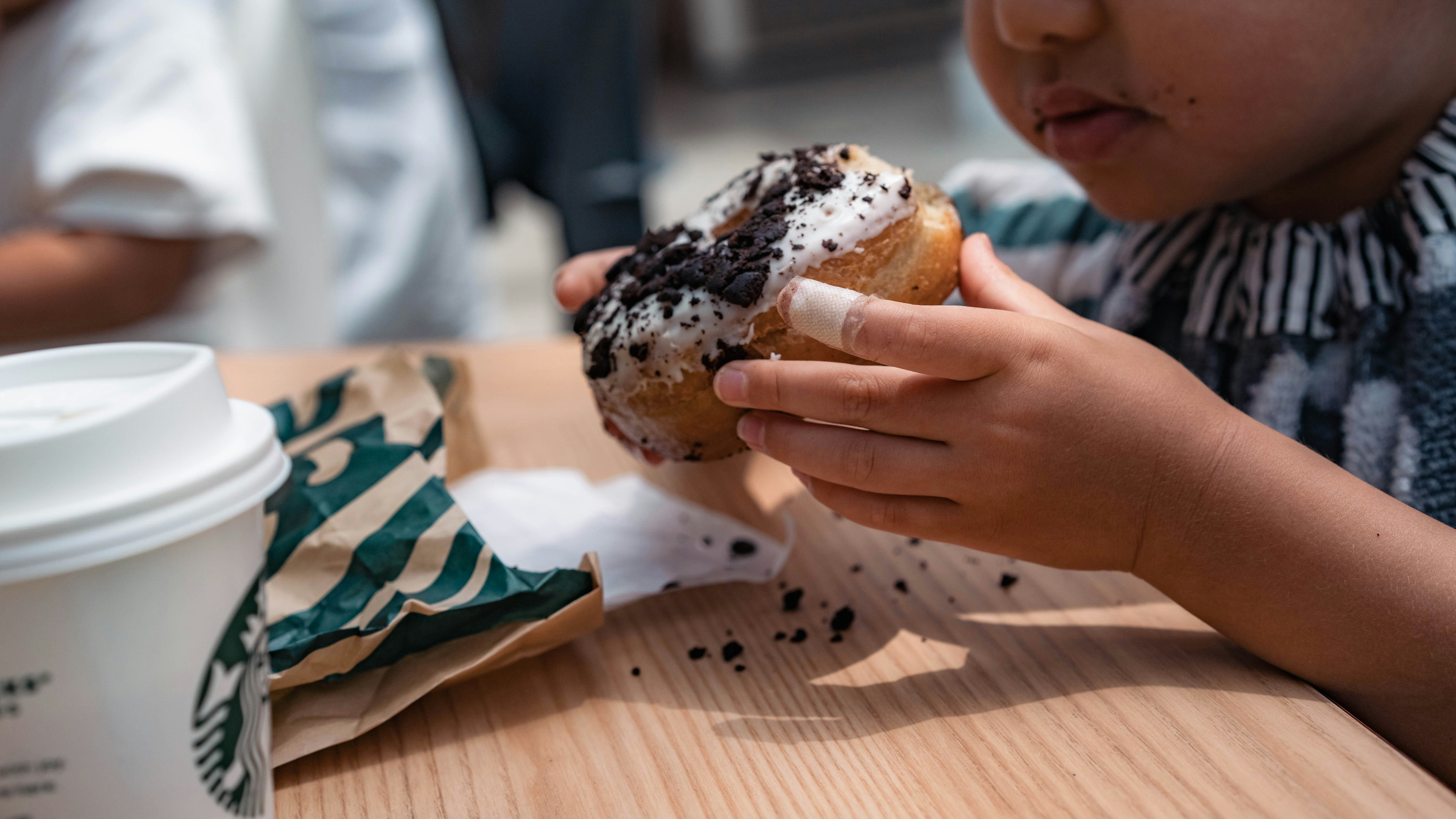enfant mangeant un beignet au sésame noir avec les mains