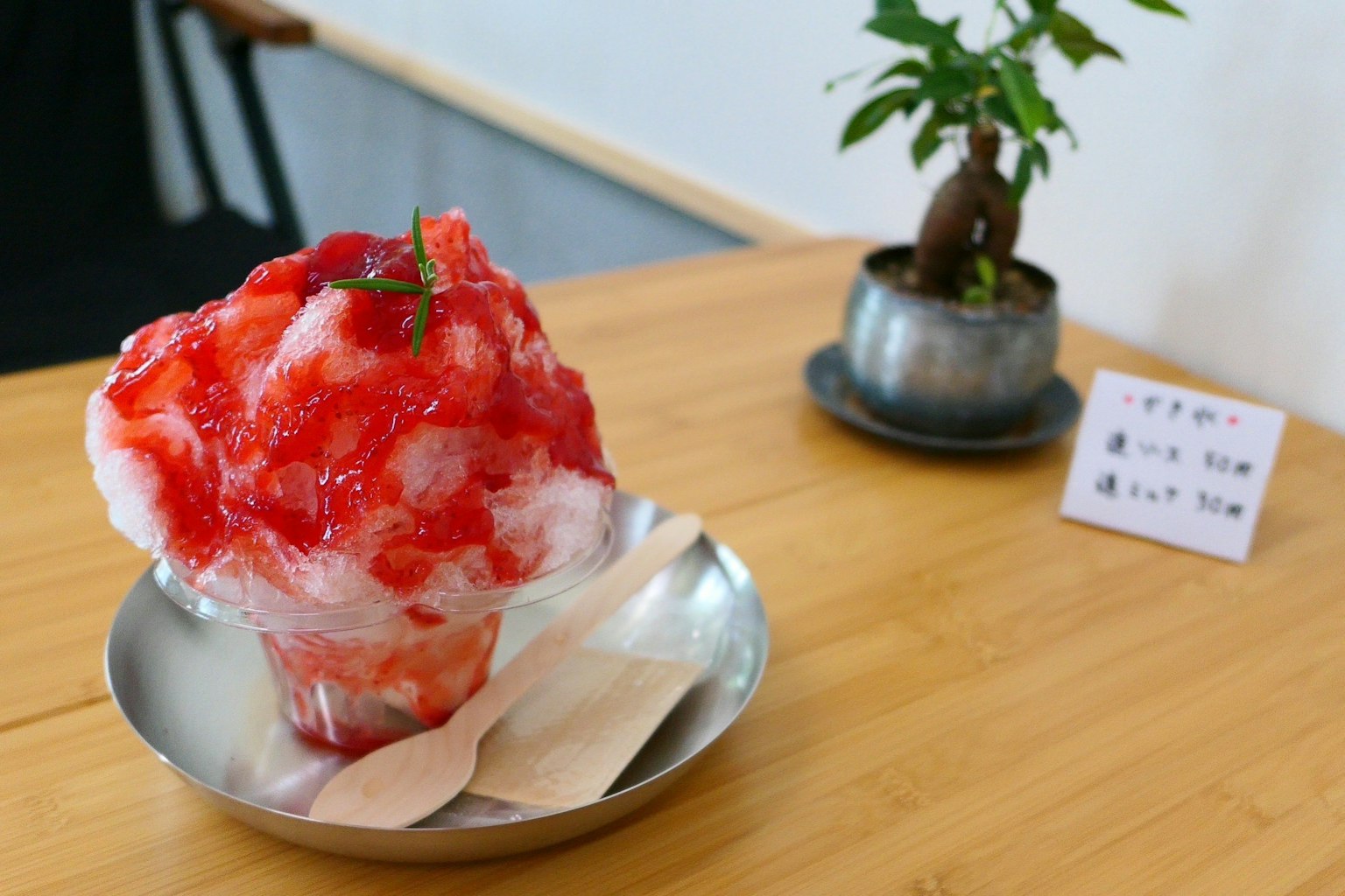 Shaved ice topped with red syrup served in a silver bowl