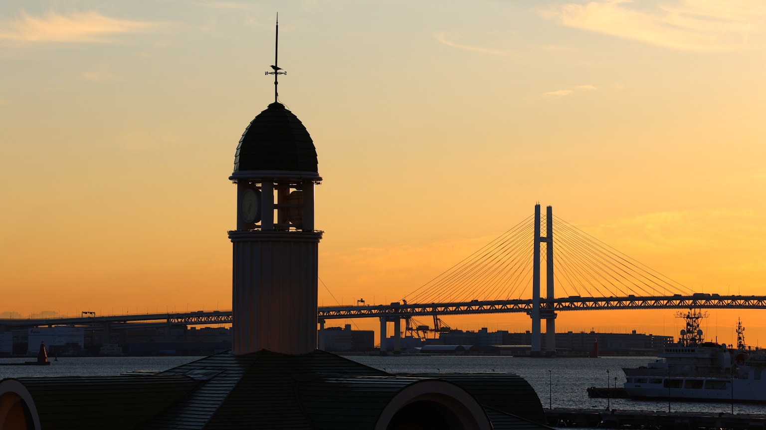 Menara dengan latar belakang matahari terbenam dan Jembatan Teluk di Yokohama