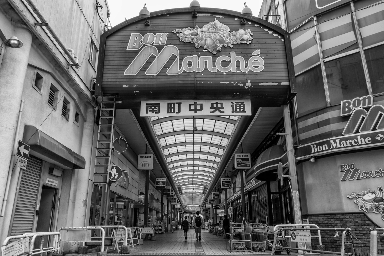 Schwarzweißbild einer Einkaufsarkade mit Bon Marché-Schild