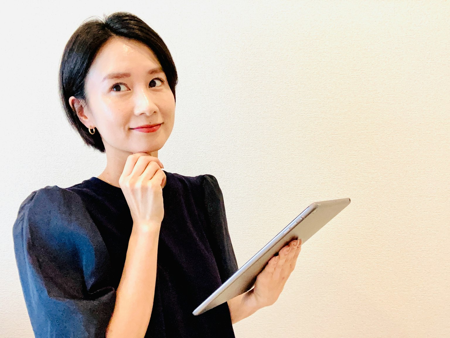 Người phụ nữ cầm máy tính bảng với biểu cảm suy tư