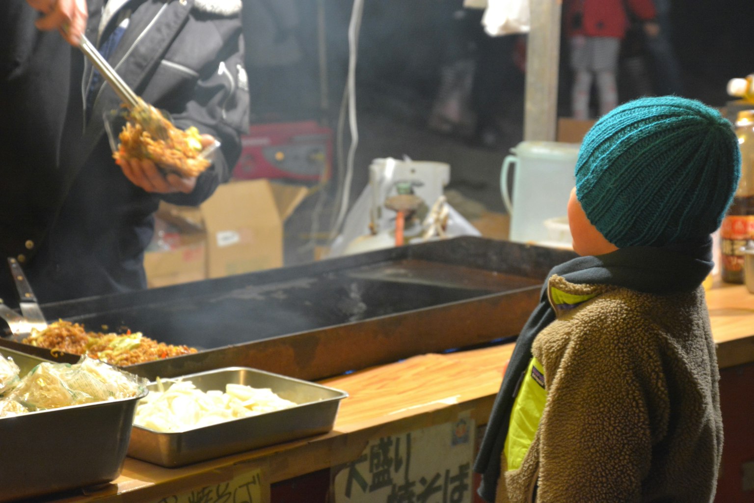 Un bambino che osserva il cibo di strada servito di notte
