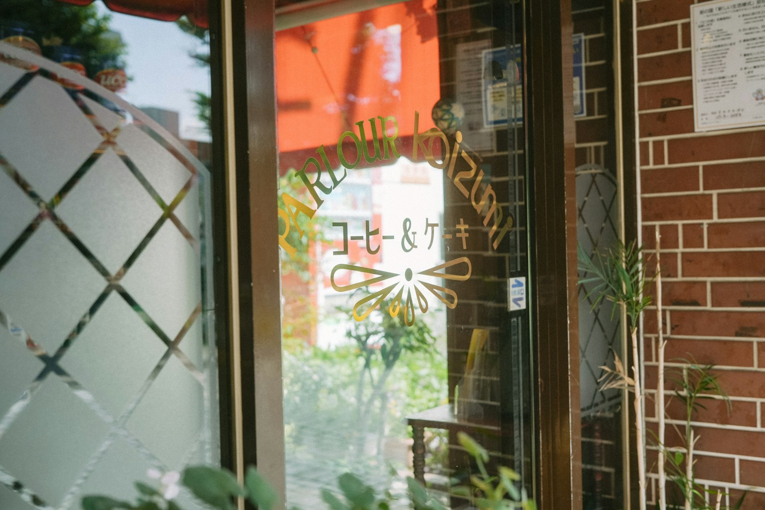 帶紅色屋頂的咖啡館入口 窗口上有標誌和可見植物