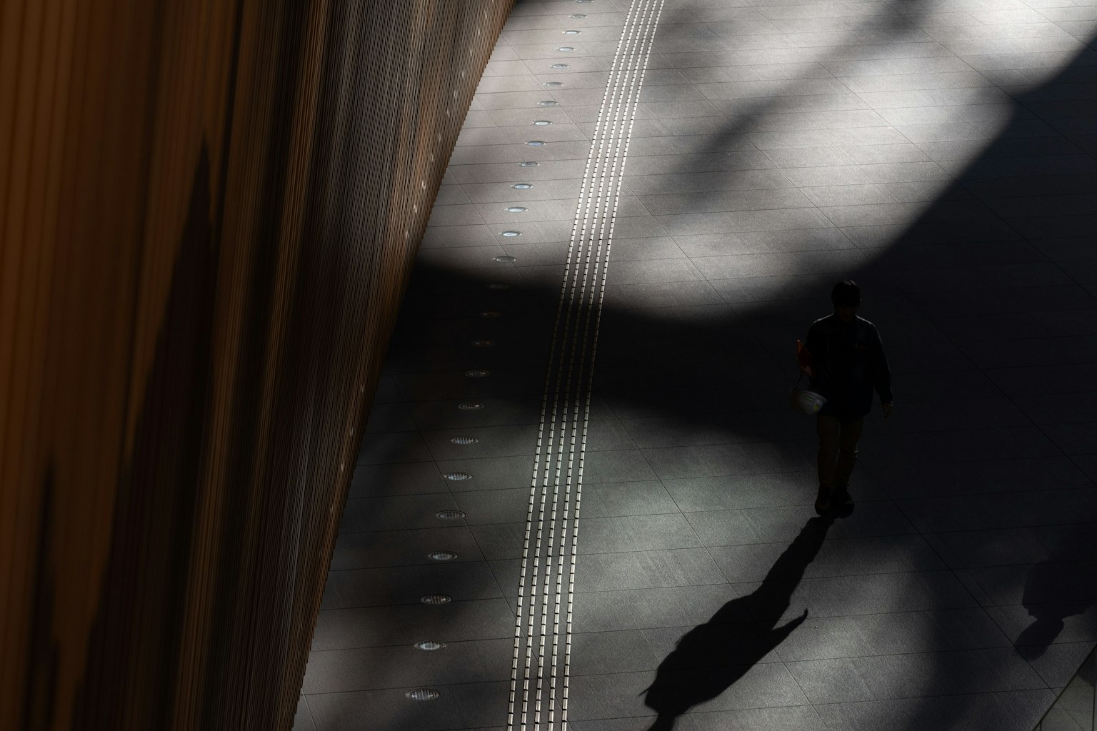 Una persona caminando en sombras con contrastes de luz impactantes en un entorno urbano