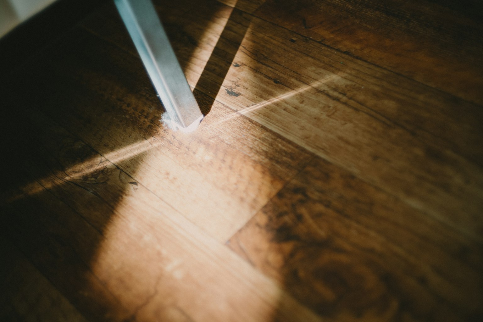 Light casting shadows on wooden floor with metal leg