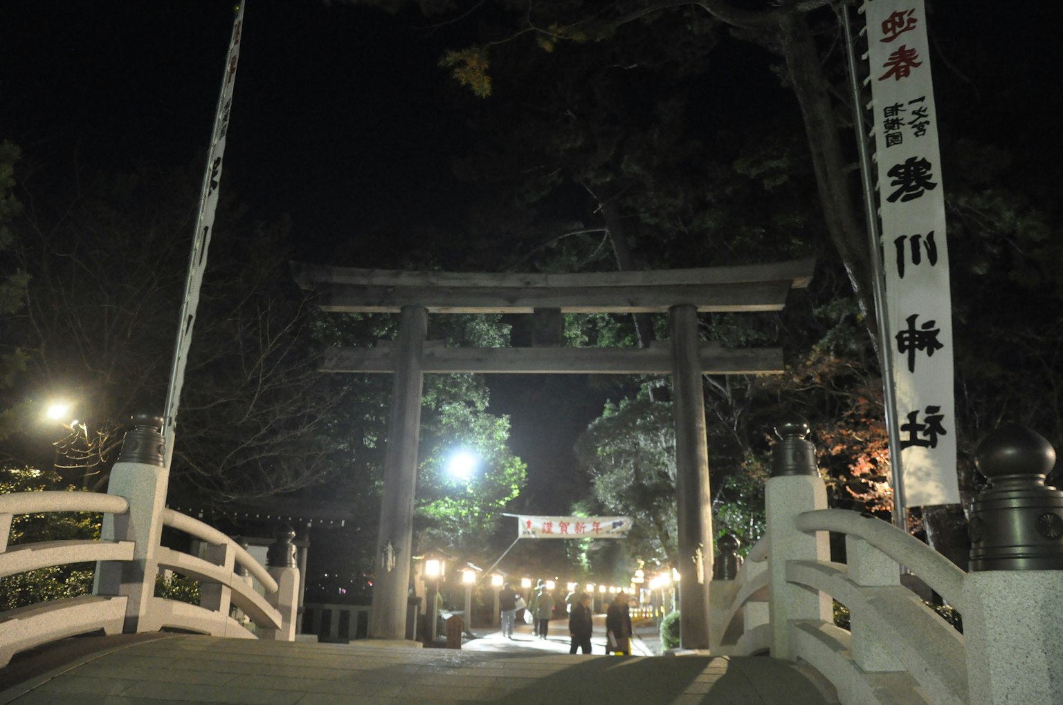 Nächtliche Ansicht eines Torii und einer Brücke mit beleuchtetem Weg