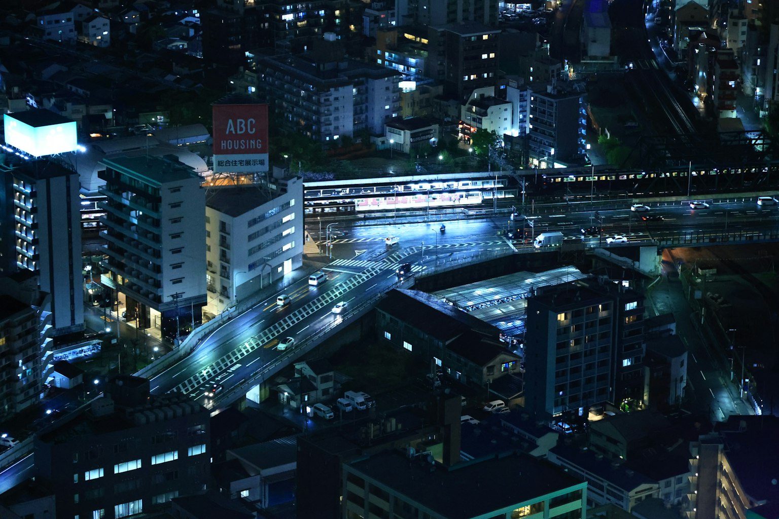 ทิวทัศน์เมืองในเวลากลางคืนที่มีสถานีรถไฟและถนนตัดกัน