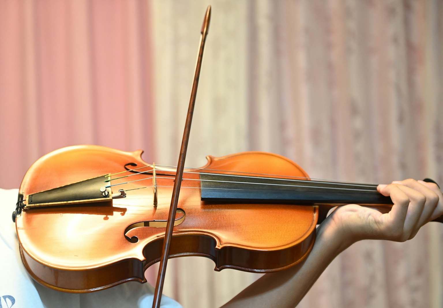 Cận cảnh bàn tay chơi đàn violin với nền màu mềm mại