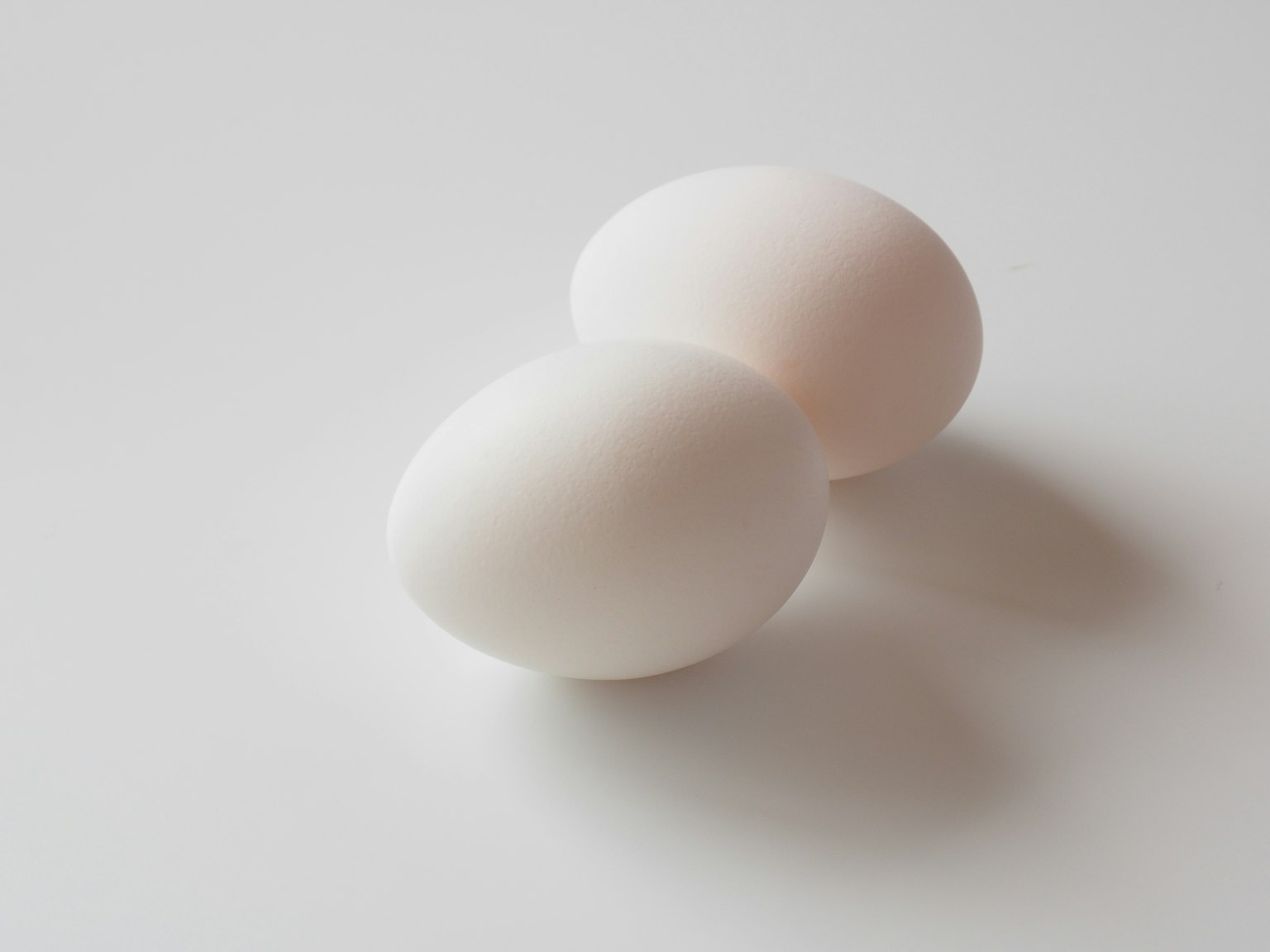 Two white eggs placed on a light surface