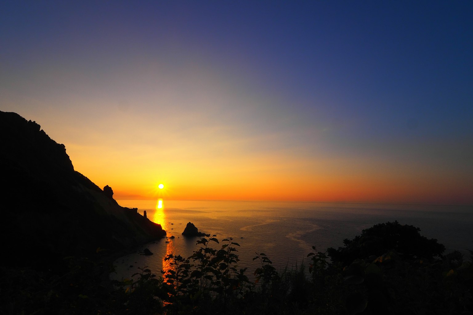 Schöne Landschaft des Sonnenuntergangs über dem Ozean mit Bergsilhouette