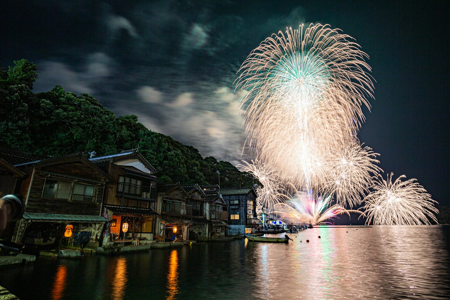 烟花照亮夜空，传统房屋坐落在水边
