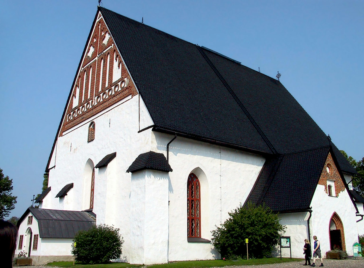 Kirche mit weißen Wänden und einem schwarzen Dach mit einem markanten dreieckigen Design und roten Fenstern