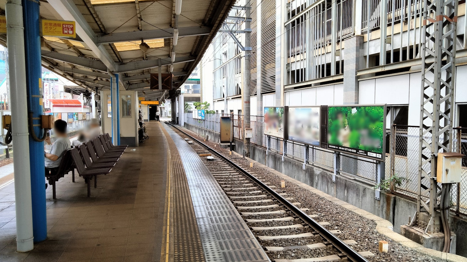 ชานชาลาสถานีรถไฟที่มีรางม้านั่งและโฆษณาเห็นได้ชัด