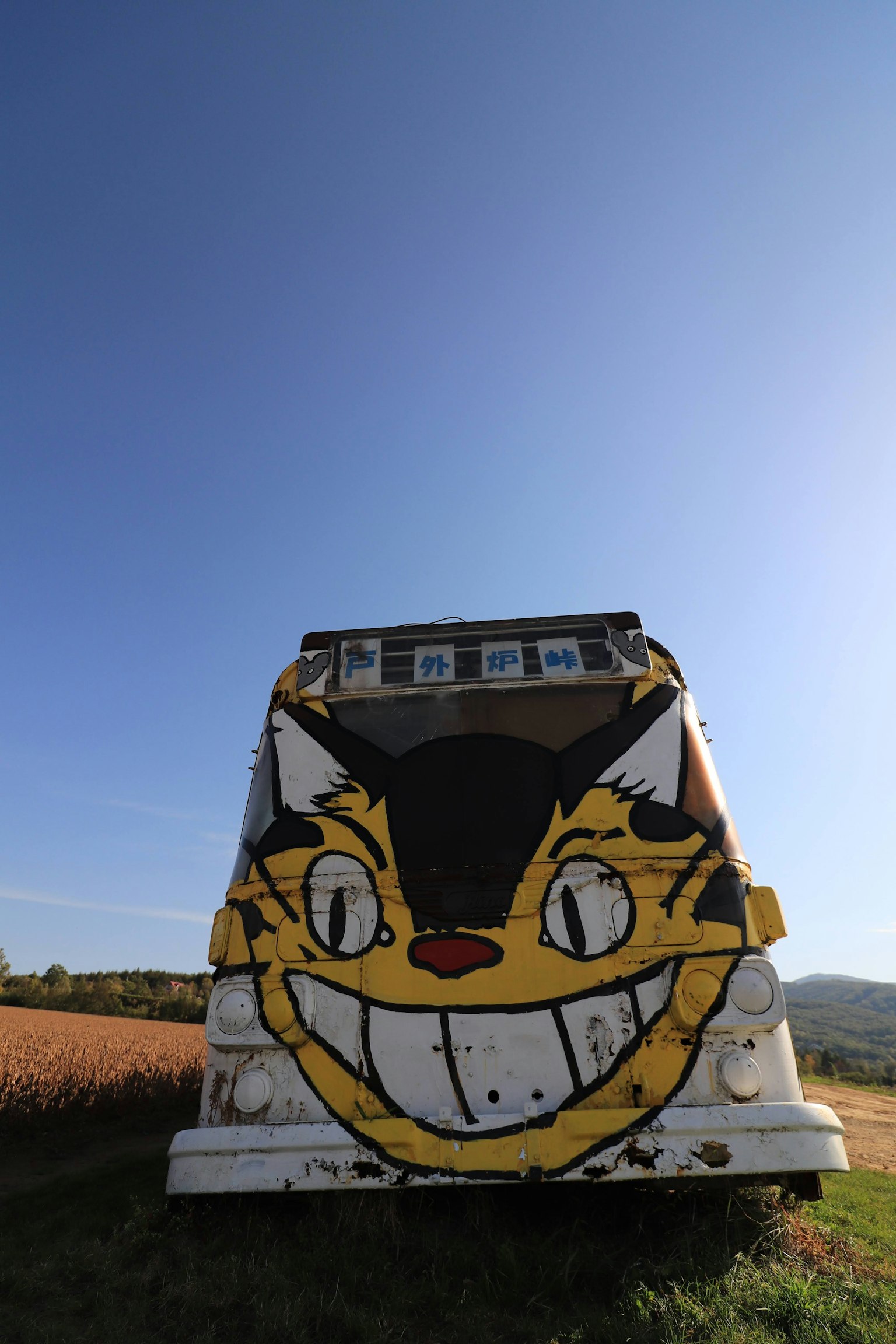 Un bus avec un graffiti d'un visage de chat sous un ciel bleu clair