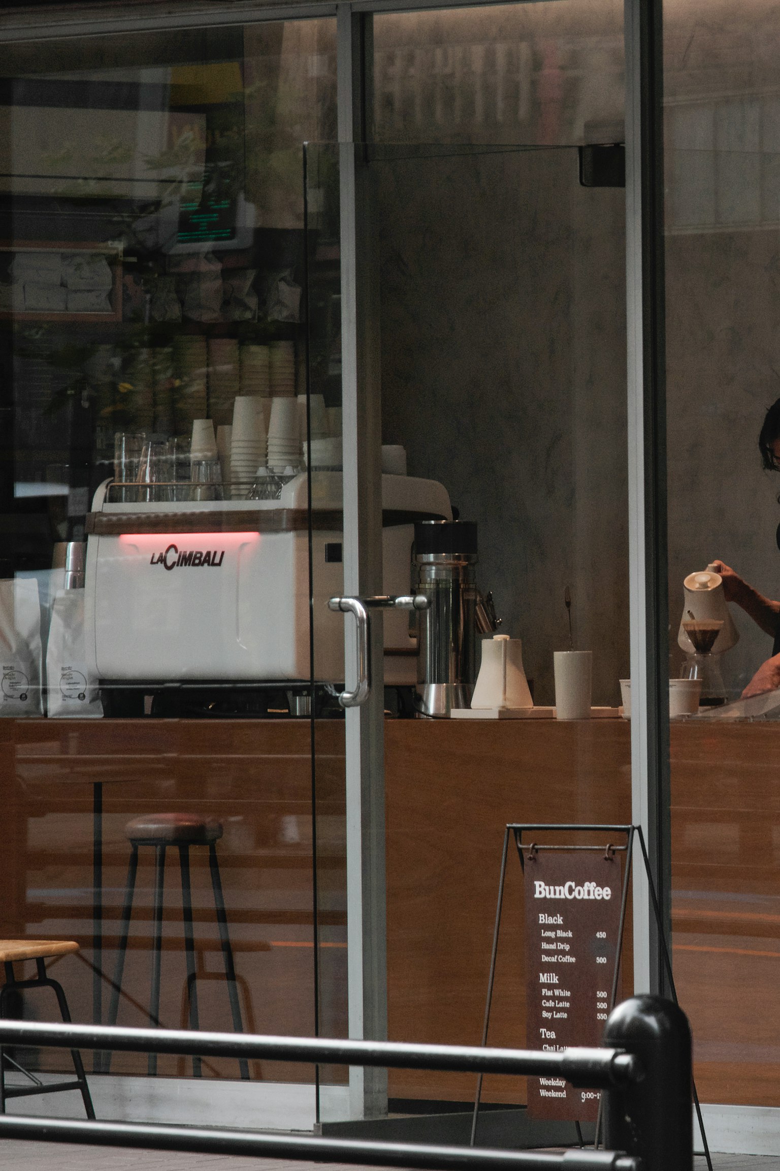 Barista yang menyiapkan kopi terlihat melalui jendela kafe