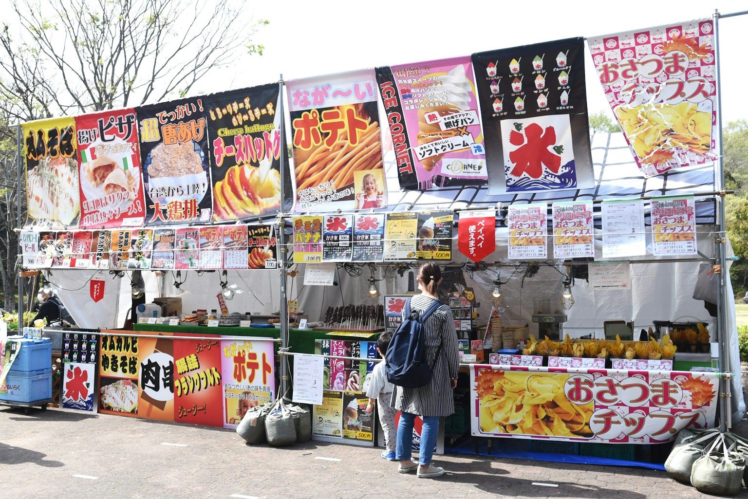 Puesto de comida con varios letreros de menú exhibidos en un entorno al aire libre vibrante
