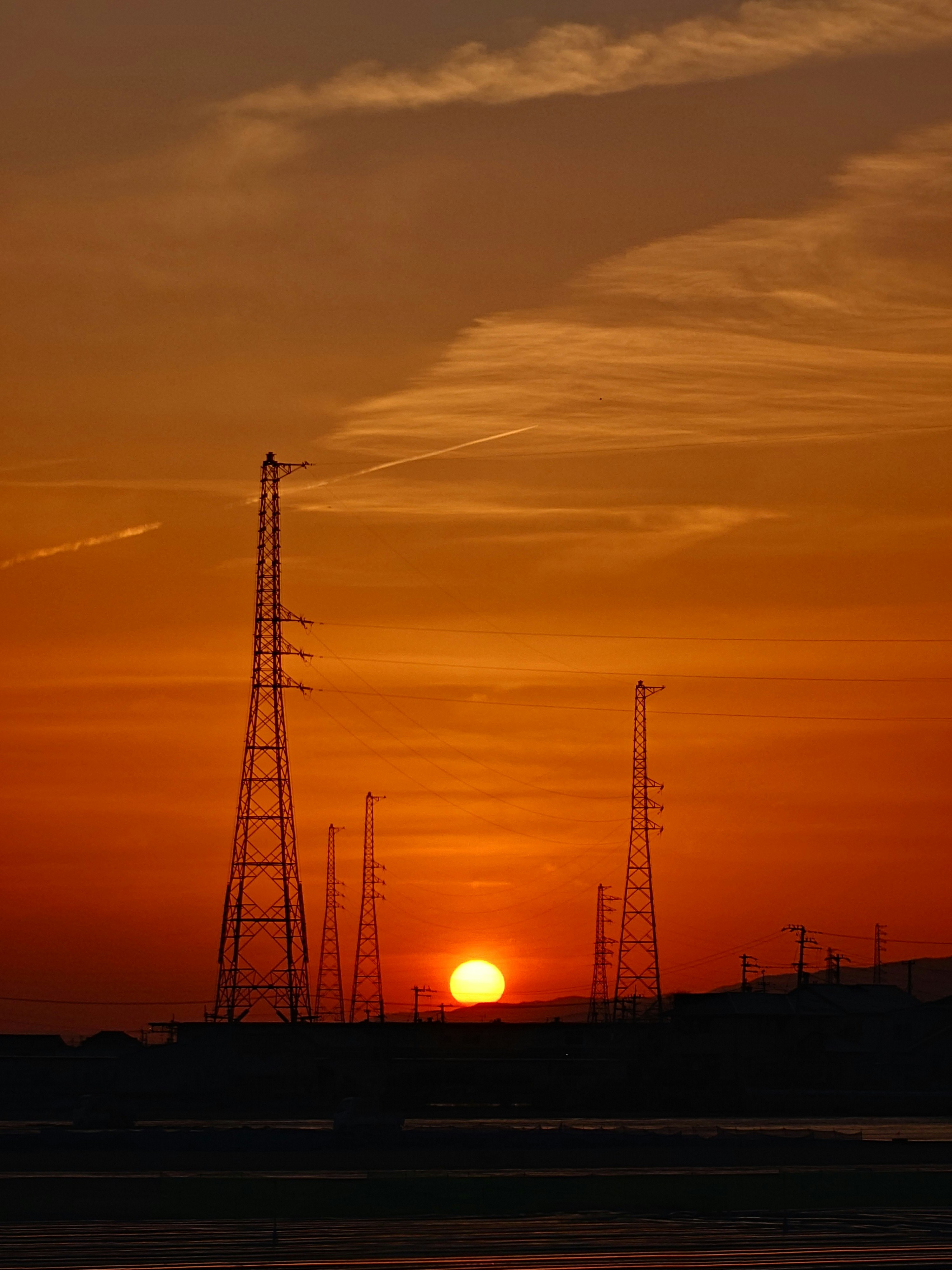 夕日が沈む中に立つ高い電波塔のシルエット
