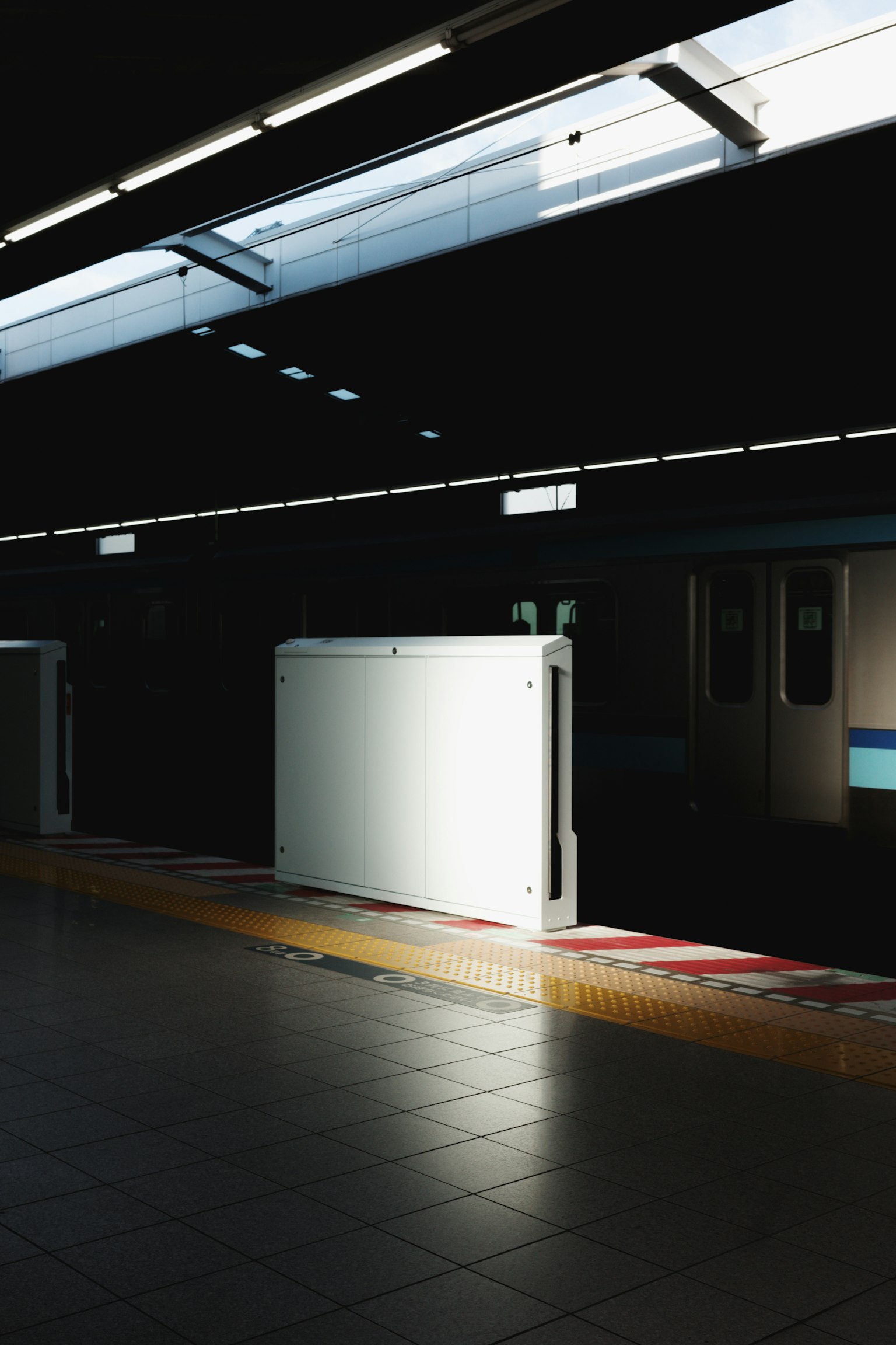 Contrast of a white gate on a dark subway platform with natural light