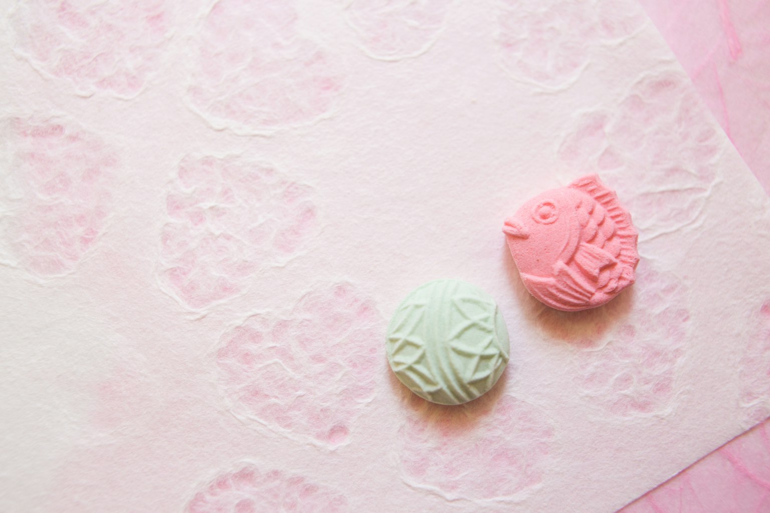 Macarons rosa e verde posati su carta a motivo di cuore