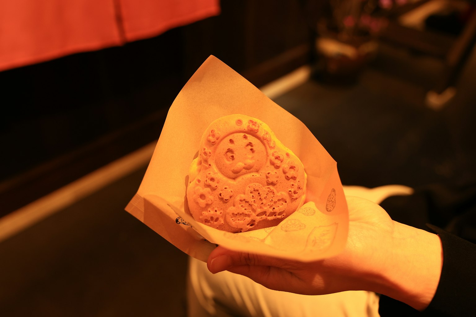 Una galleta en forma linda sostenida con la mano con diseños intrincados