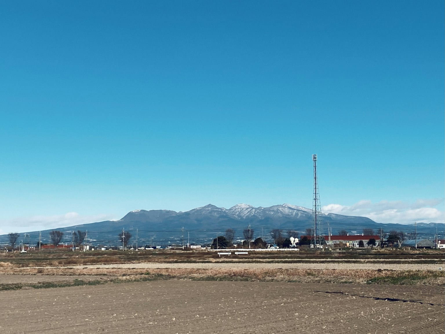 Bergkette unter klarem blauen Himmel mit ländlicher Landschaft