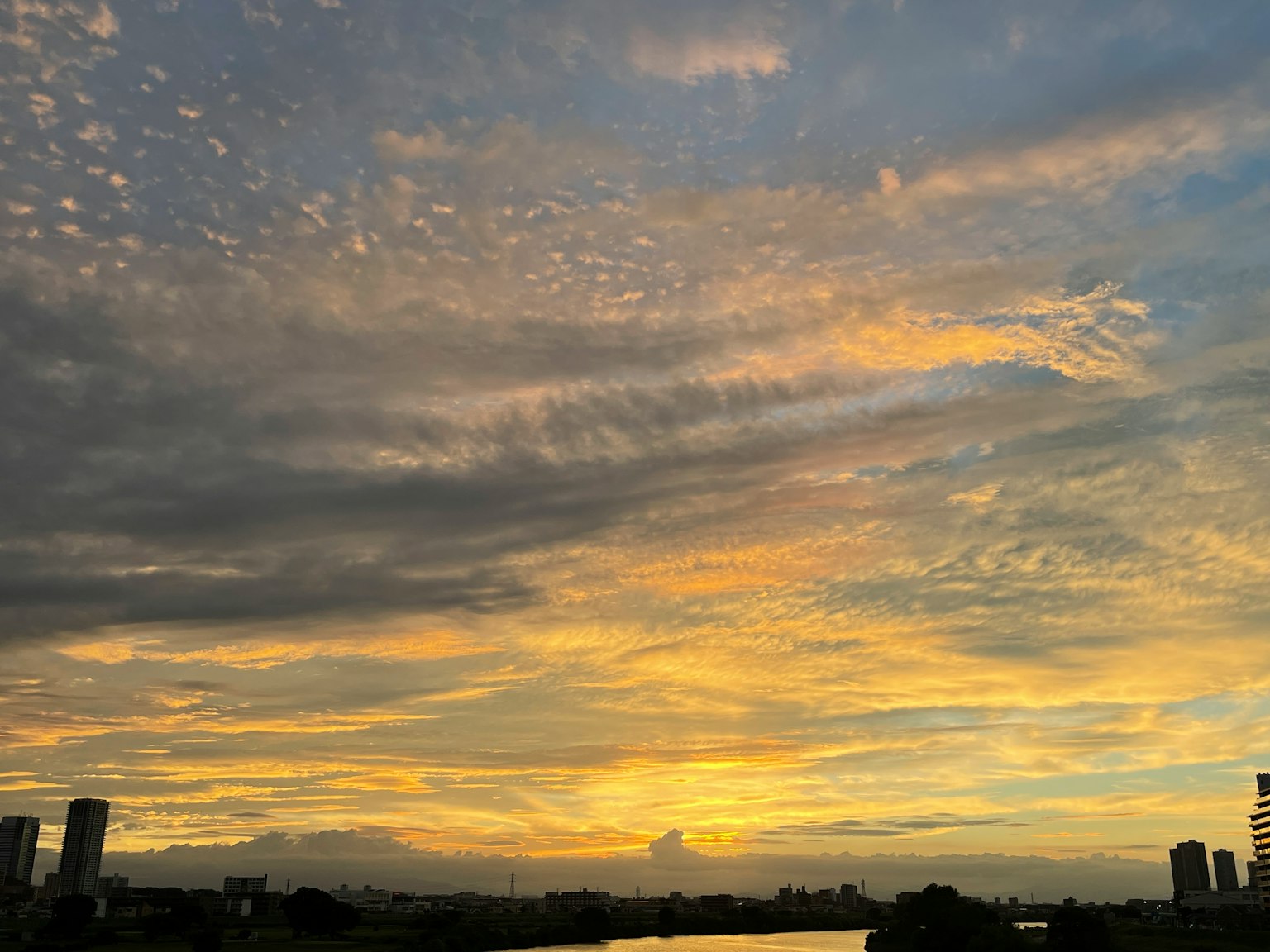 Lebendiger Sonnenuntergangshimmel mit bunten Wolken und Silhouetten von Gebäuden