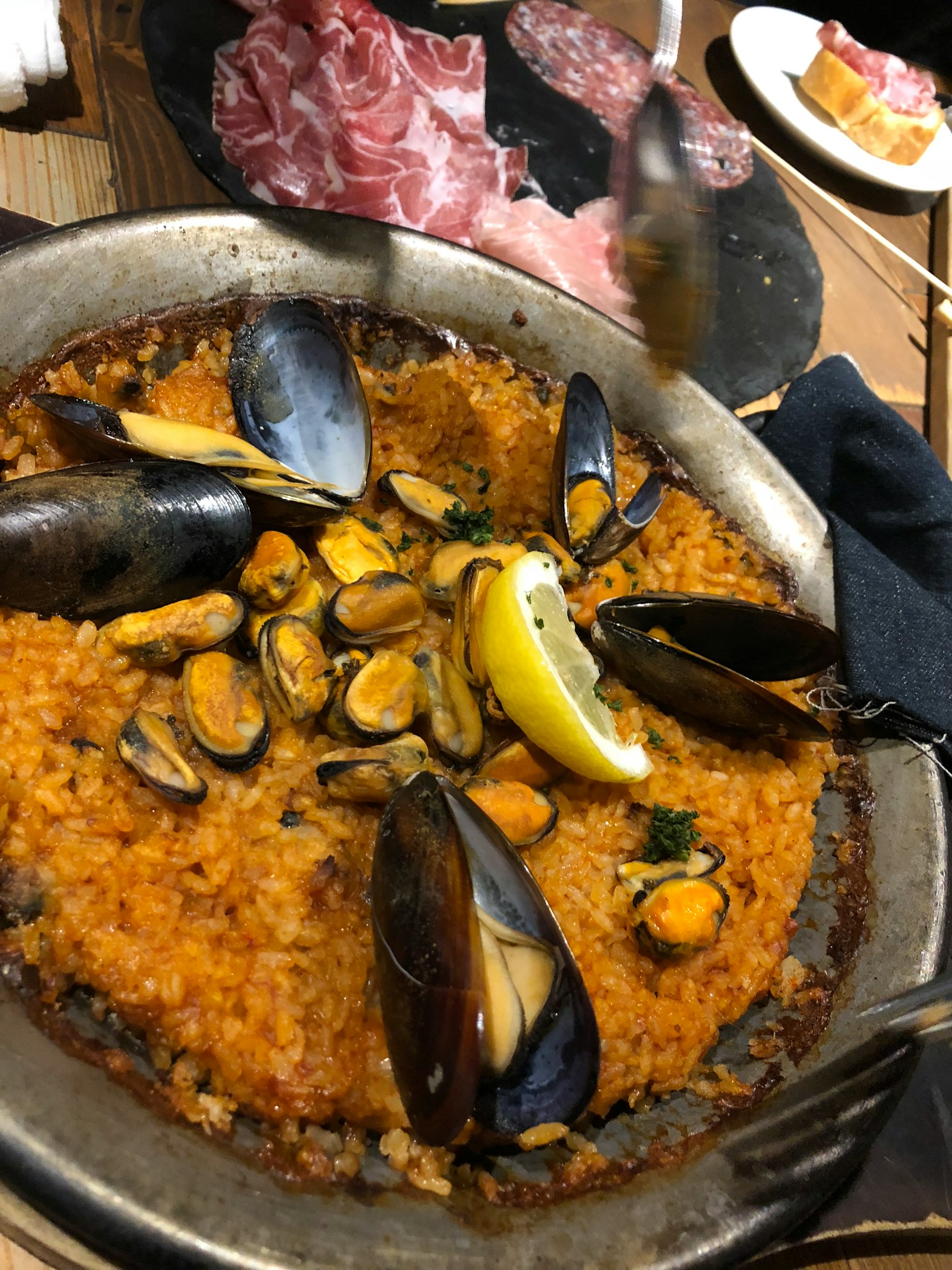 A delicious paella dish featuring mussels and lemon garnish