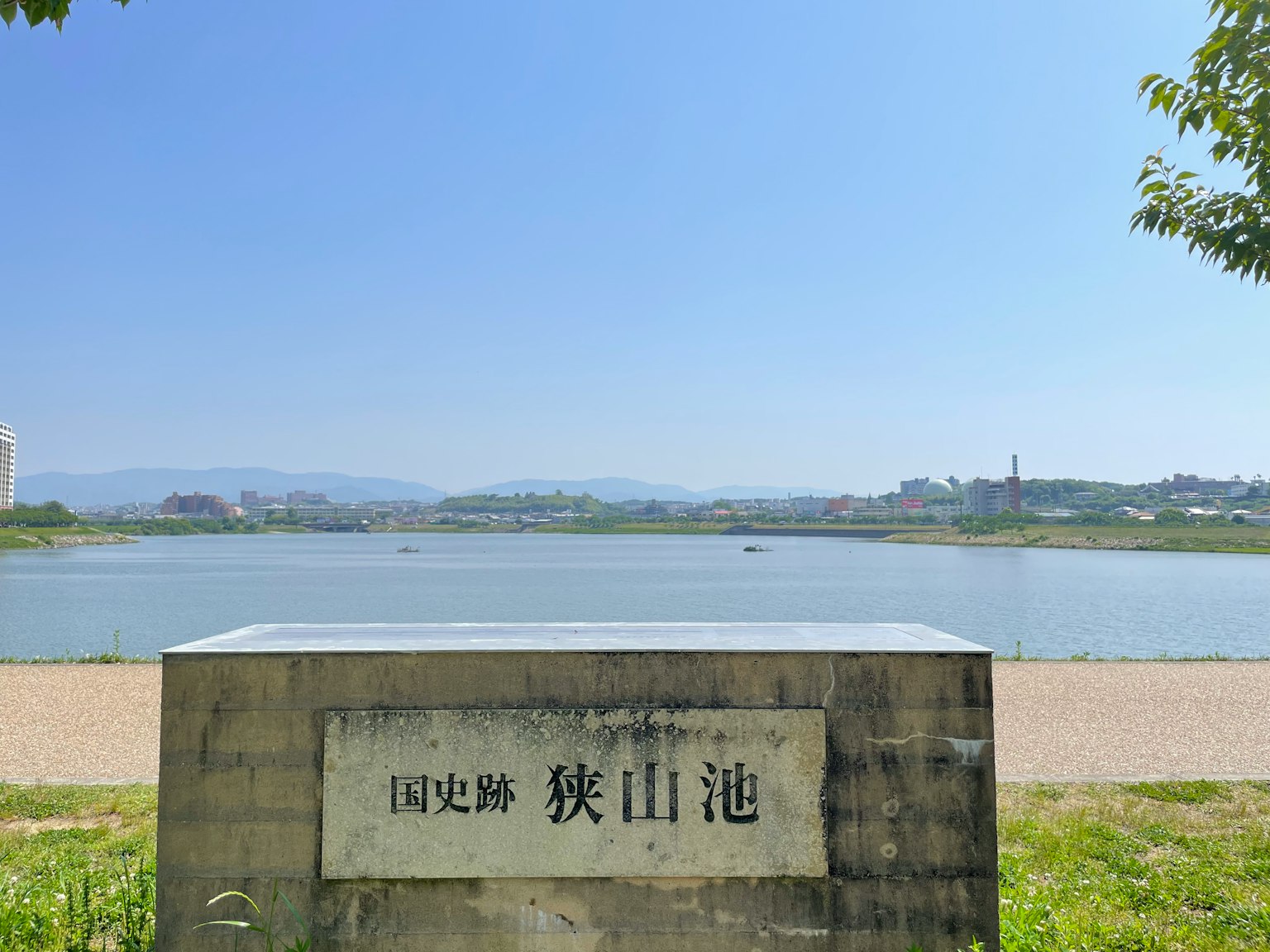 石碑上刻有池塘名称的风景，蓝天清澈