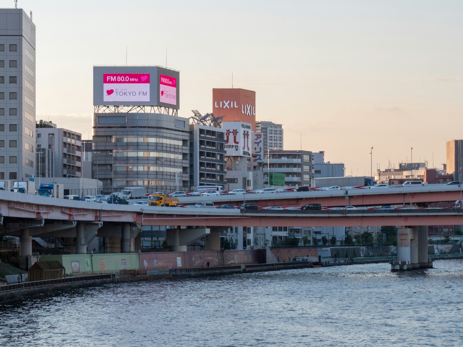 黃昏城市風景，河流和帶廣告的高樓大廈