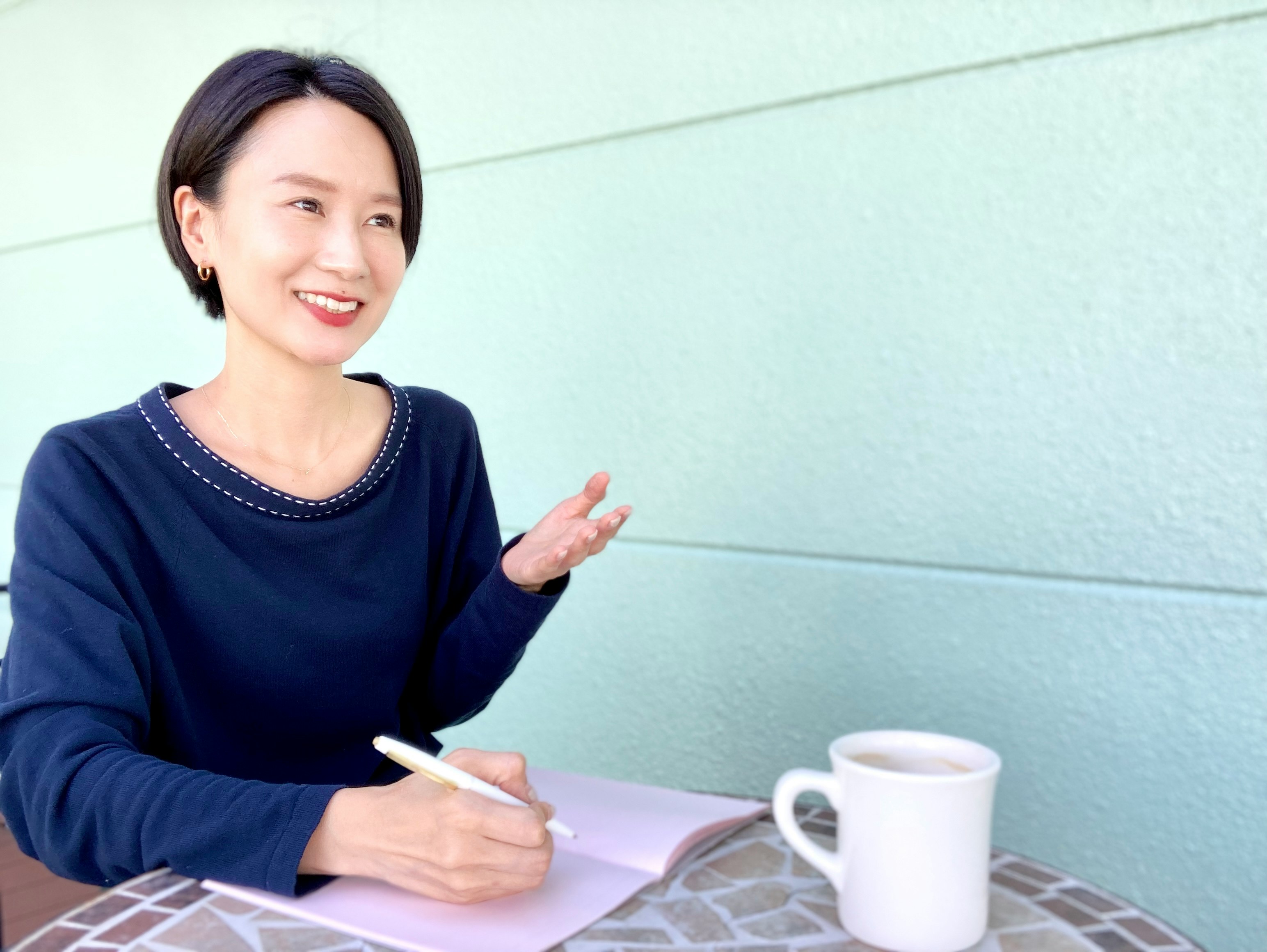 Woman writing in a notebook at a cafe table