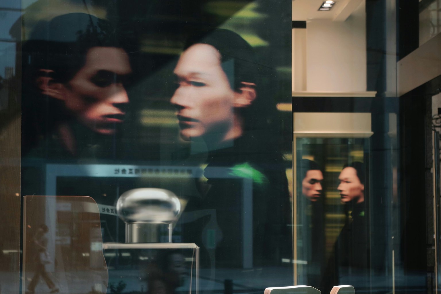 Stadtlandschaft mit den Gesichtern zweier Männer, die in einem Glasfenster reflektiert sind