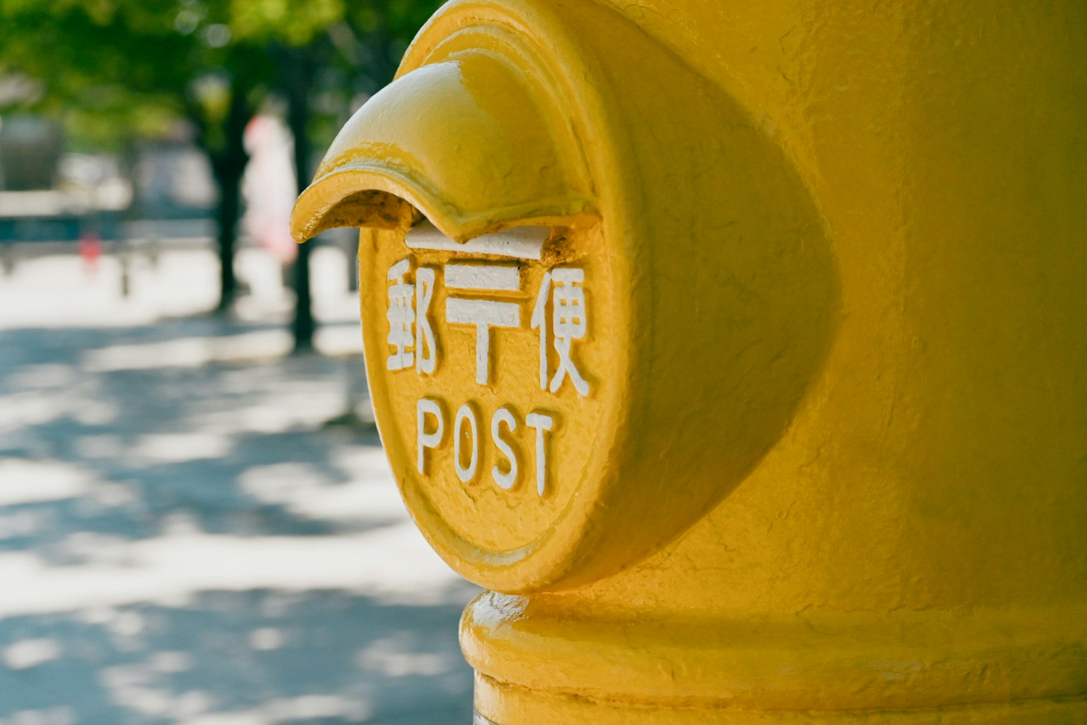 Close-up of a yellow mail post with postal markings and the word POST in English
