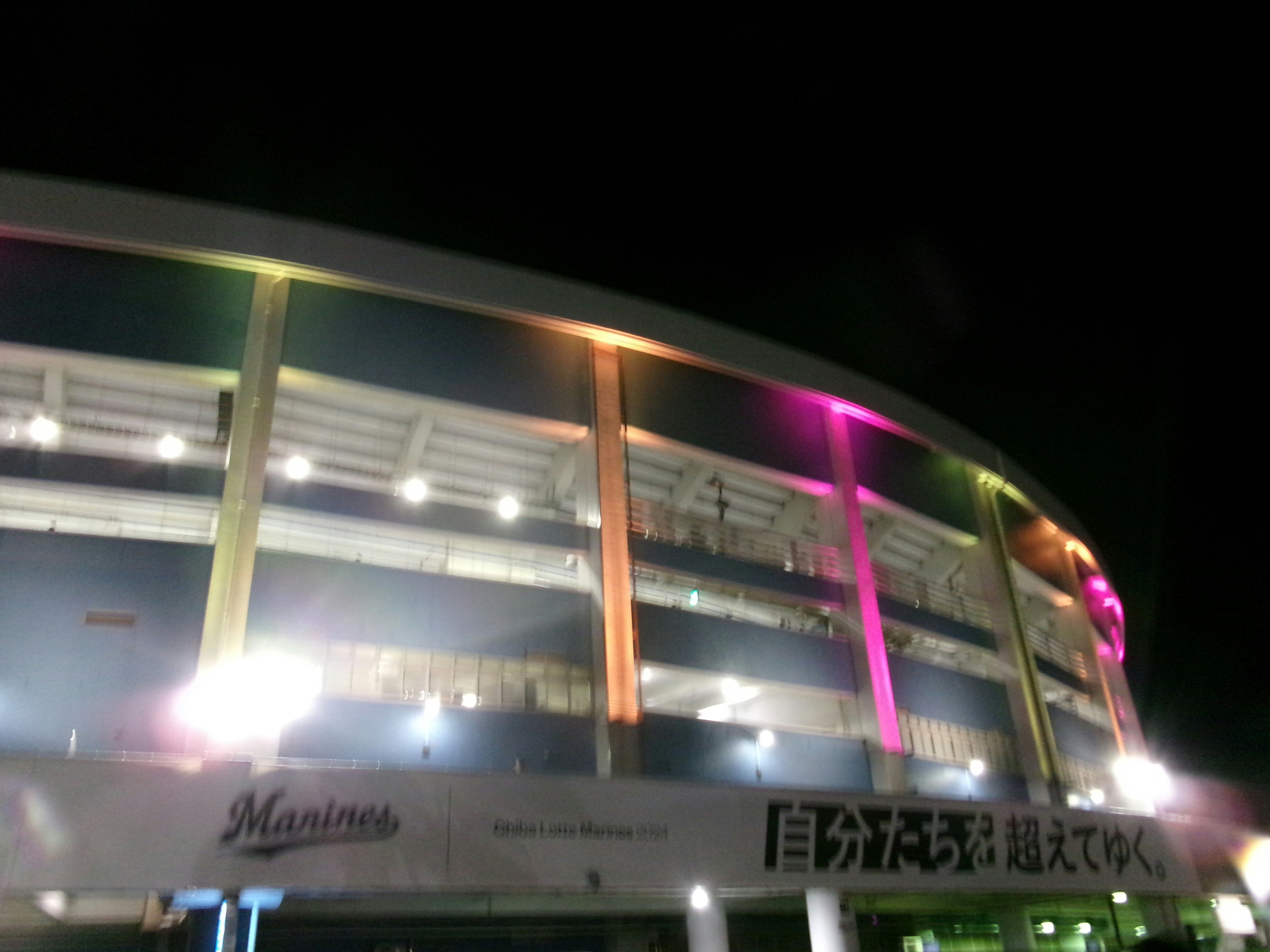 夜の屋外で光る高架の建物と看板のある通路